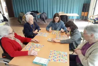 2 jeunes et des rédidents qui jouent au Skyjo